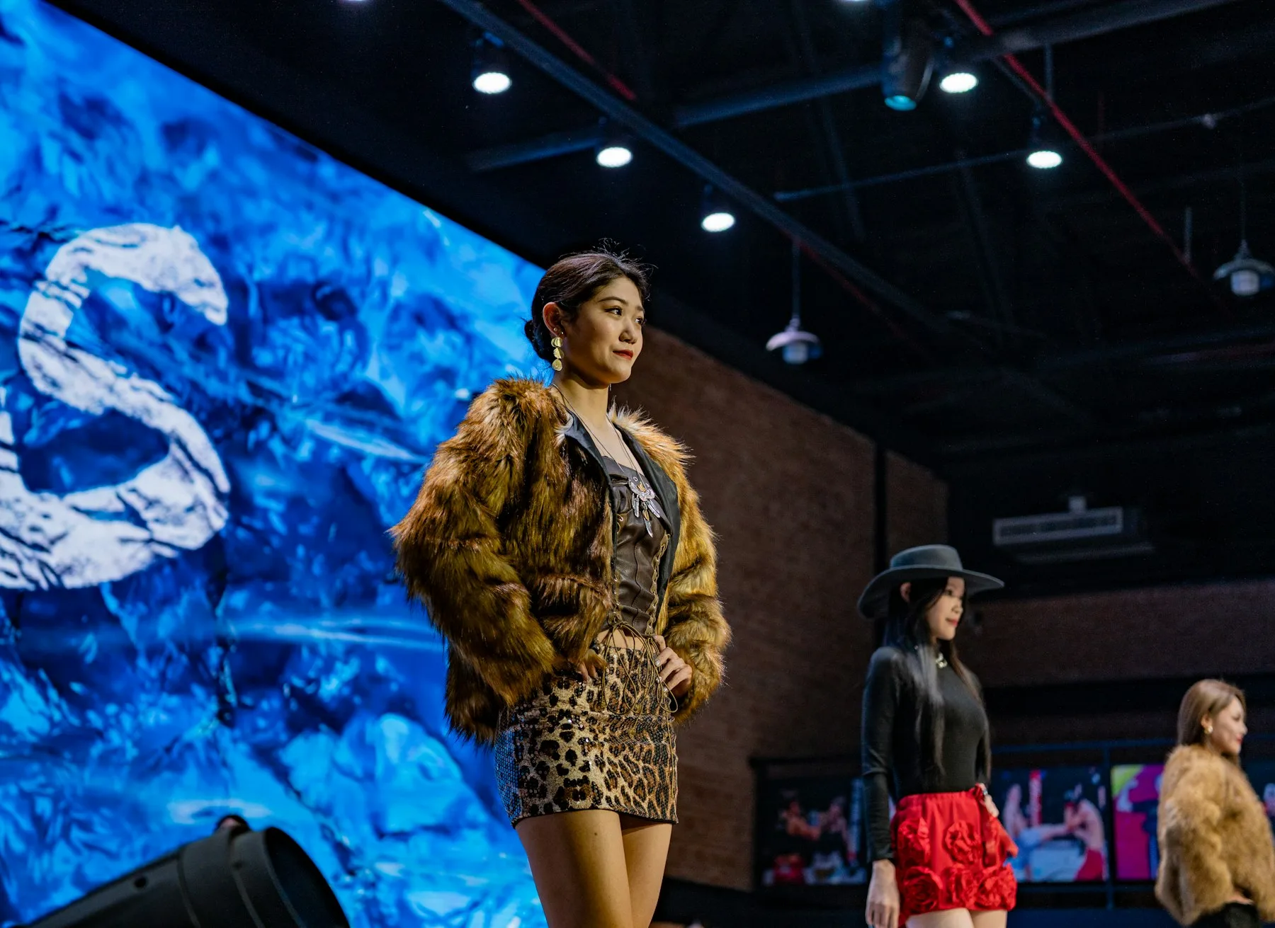 Models on a runway in faux fur, a leopard-print sequin skirt and a wide-brim hat